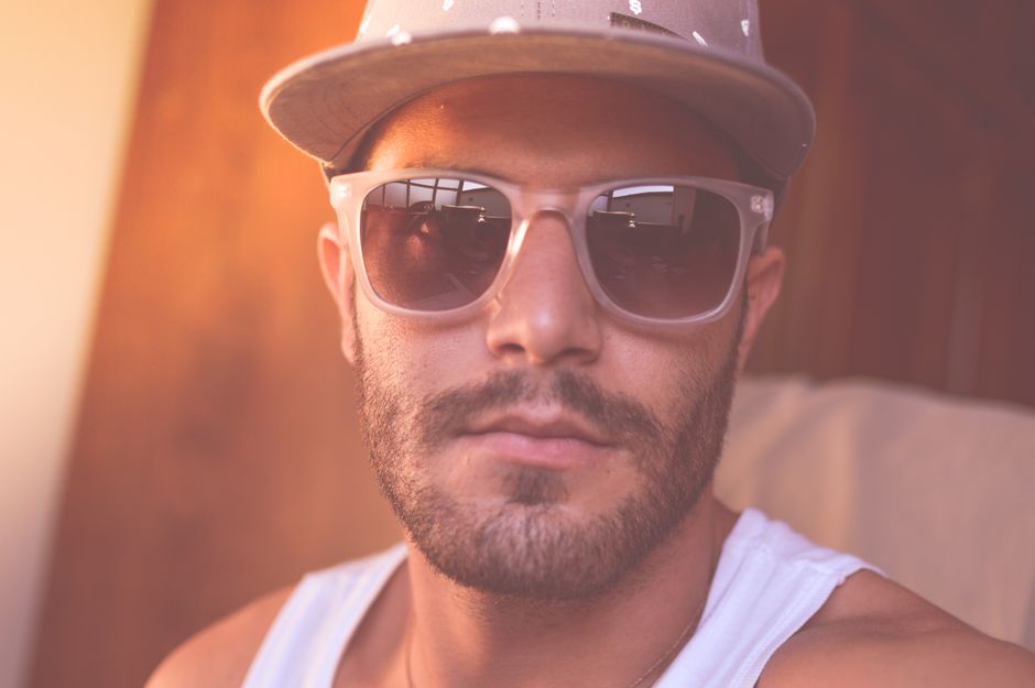 A man wearing sunglasses and a hat in a stylish and casual portrait.