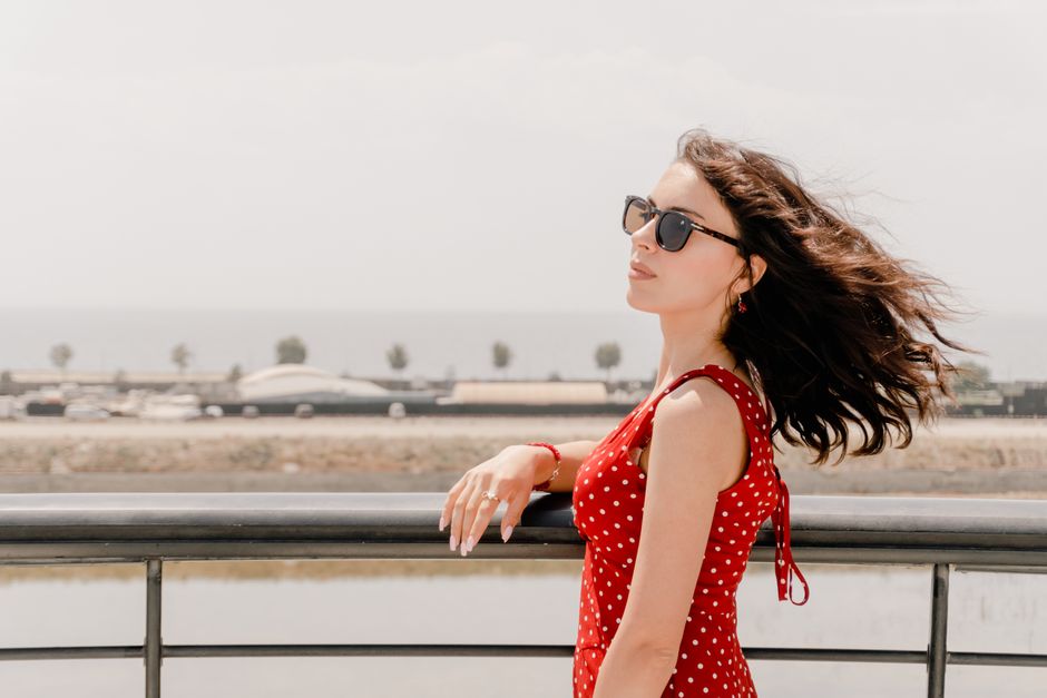 A woman in a red polka-dot dress enjoys a sunny day by the seaside in Baku, Azerbaijan.