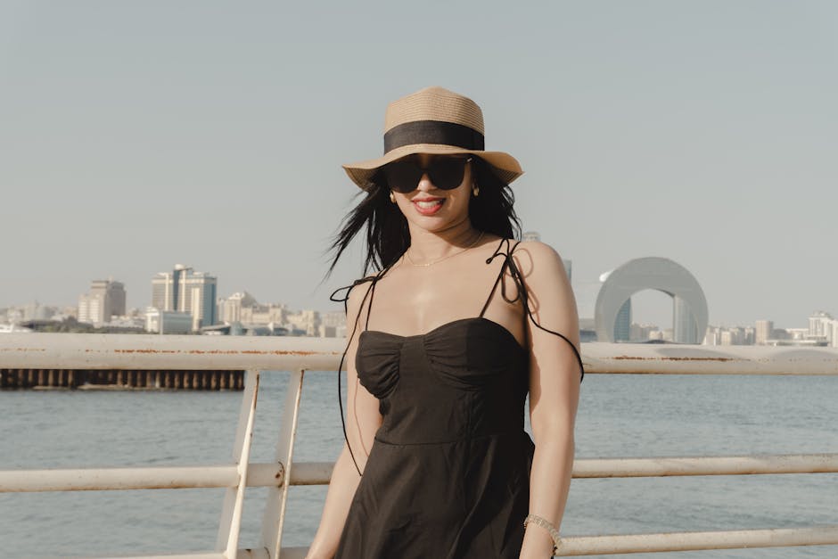 A fashionable woman in a sunhat enjoys a sunny day with Baku's skyline in the background.