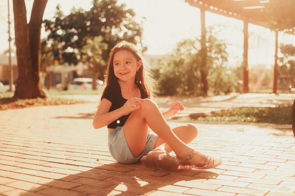 A happy girl enjoying a sunny day outdoors on a brick path.
