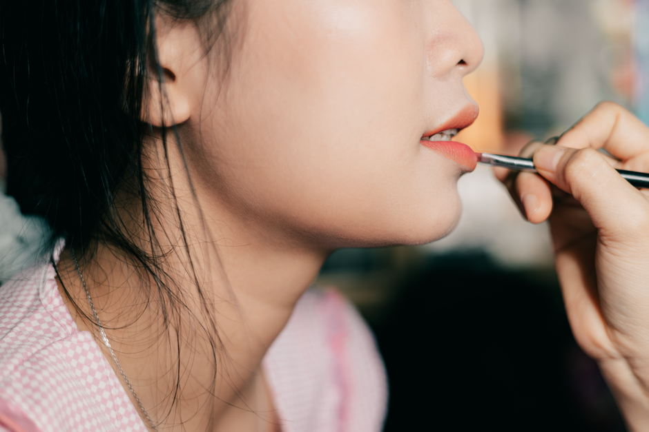 Close-up of a woman applying lipstick, showcasing beauty and cosmetics.