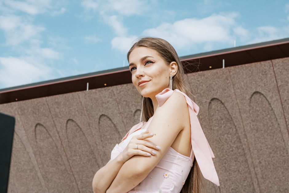 Confident young woman in stylish dress posing outdoors against a modern architectural back