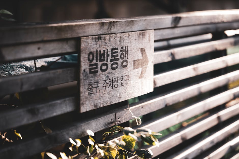 Wooden fence with a directional sign in Korean lit by sunlight.