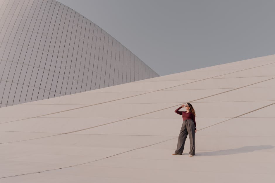 Stylish woman standing in front of modern architectural structure outdoors.
