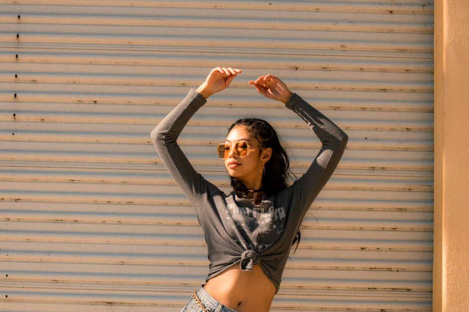 Confident woman in casual fashion posing with sunglasses on a sunny day.