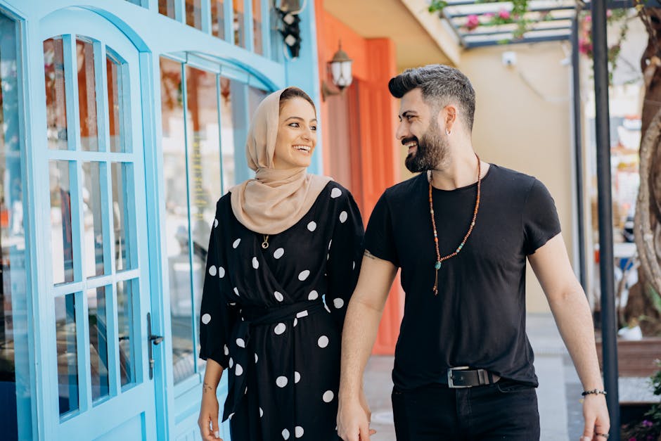 A stylish Muslim couple holding hands and walking outdoors with joy.
