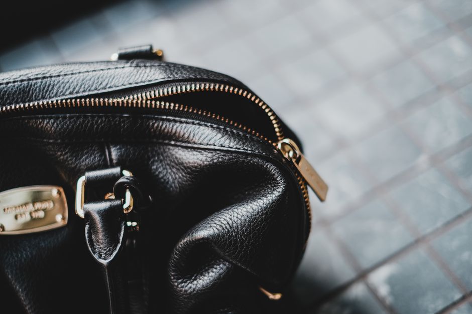 Close-up of a stylish black leather bag featuring a zipper and metal tag.
