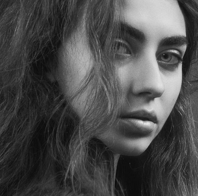 Close-up black and white portrait of a young woman with deep expression.