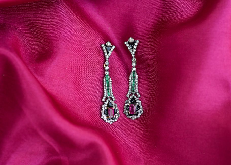 Luxurious emerald and ruby earrings with diamonds on a pink silk background. Perfect for h