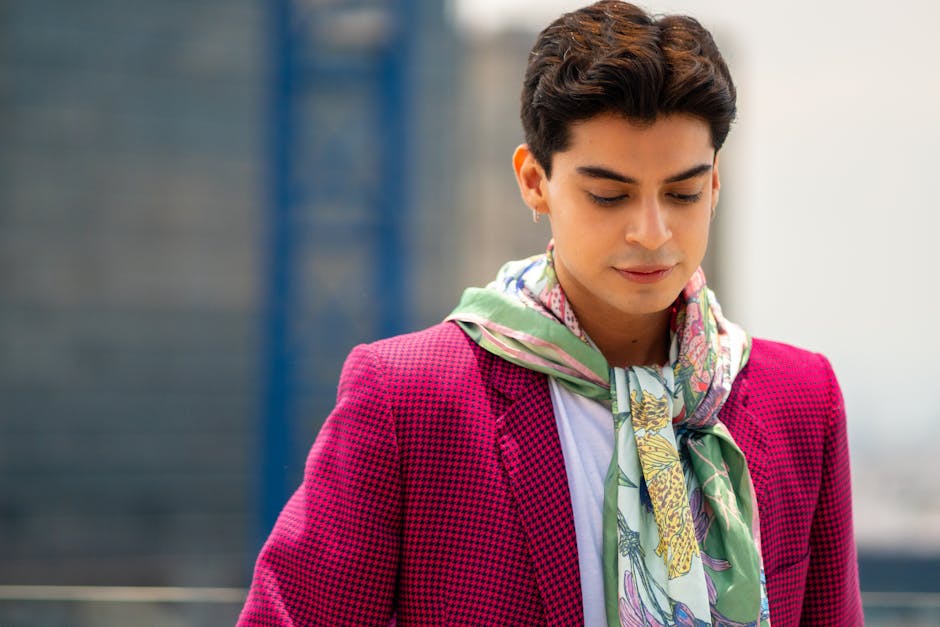 A fashionable man posing in Mexico City, wearing a pink jacket and floral scarf.