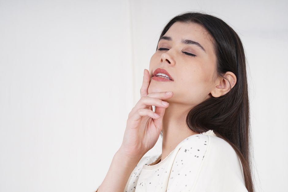 Serene portrait of a woman with long hair, eyes closed against a white background.