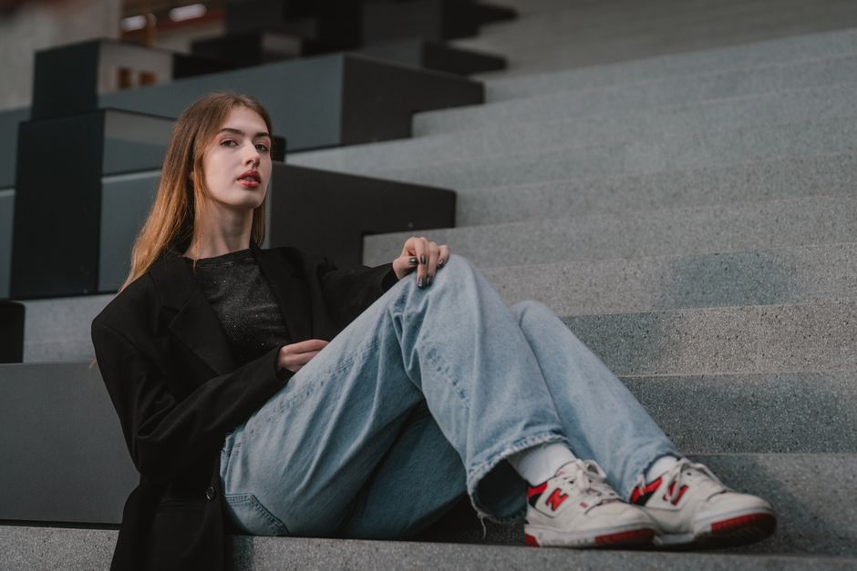 Stylish woman sitting on urban steps, showcasing modern casual fashion in Vienna.