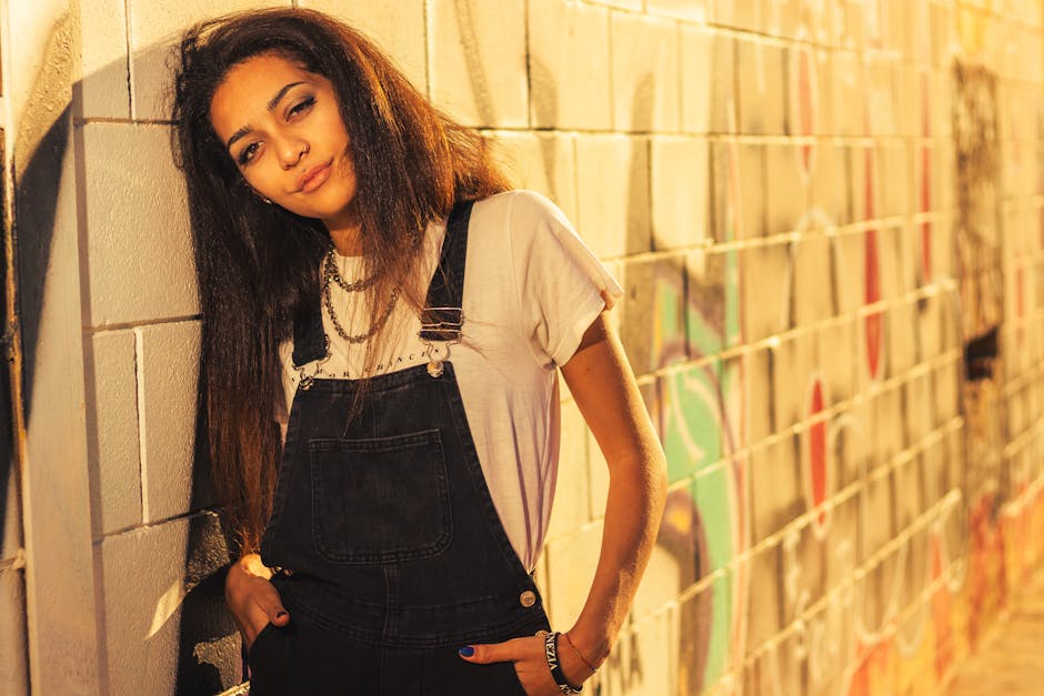 Hispanic teenager in casual fashion poses confidently by a graffiti wall in Valencia, showcasing urban style.