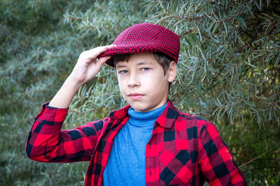 Portrait of a boy wearing a red checkered hat and shirt, outdoors, expressive look.