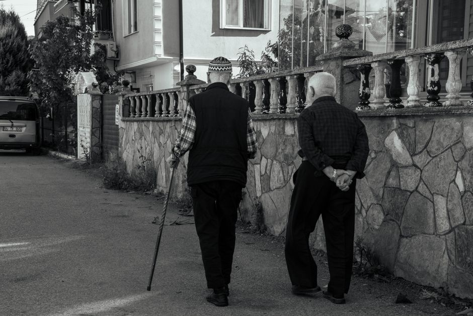 Elderly men walking along a stone wall, sharing companionship and conversation.