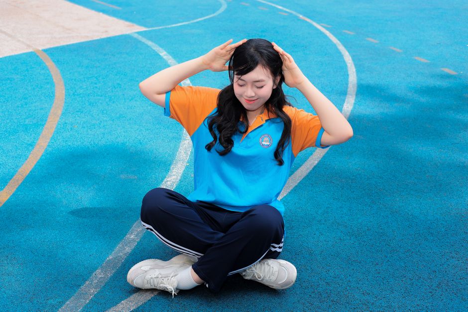 A young woman meditates peacefully outdoors on a vibrant blue track.
